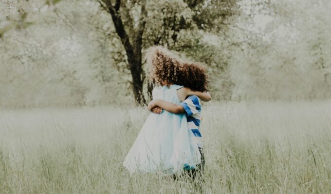 Two children with curly hair hugging