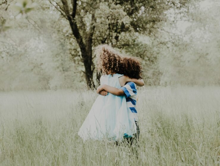 Two children with curly hair hugging