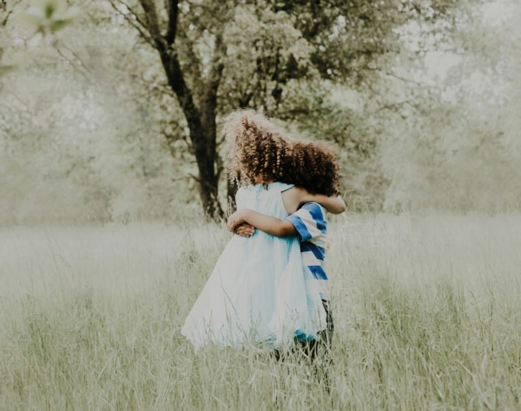 Two children with curly hair hugging